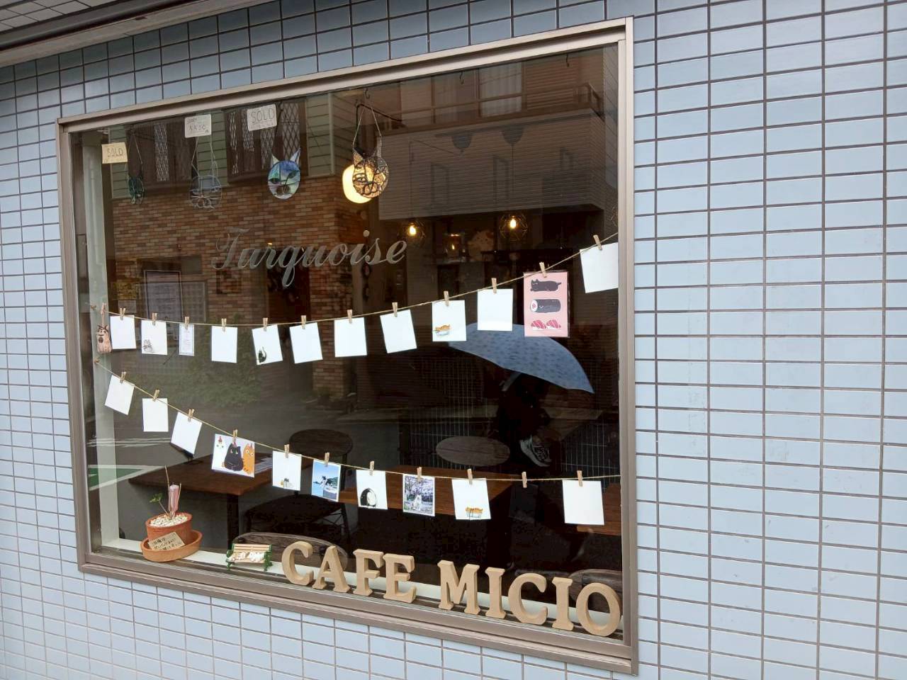 カフェ ミーチョ 店頭：窓ガラス越しに金色の CAFE MICIO レター